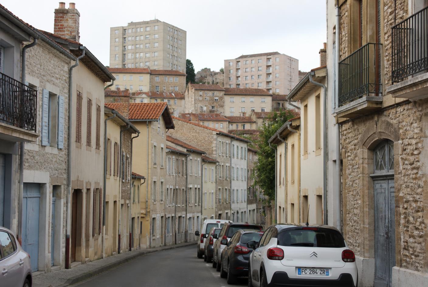 Rue en pente de la vieille ville de Vienne : façades en pierre, toits de tuiles et immeubles des années 1970 en surplomb